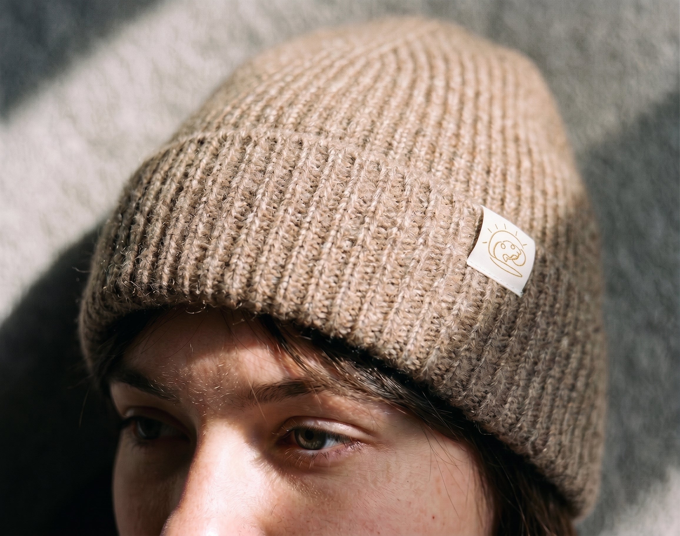Close-up of the Natural Beige cashmere beanie showing the ribbed knit and FRUAA label