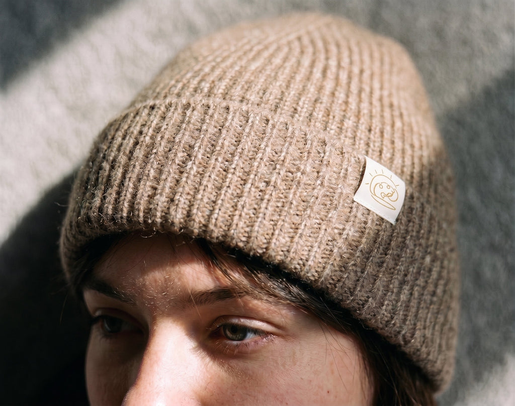 Close-up of the Natural Beige cashmere beanie showing the ribbed knit and FRUAA label