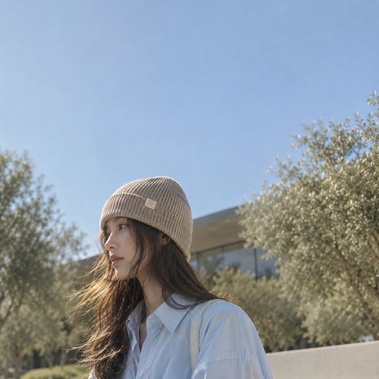 Model wearing the FRUAA Natural Beige cashmere beanie outdoors under a clear sky